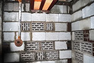 Blick ins Innere: Wände aus großen Betonsteinen, von denen einige Ritzen haben.Von der Decke hängt ein Eisenrohr.